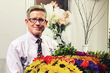 A member of the Nanz & Kraft management team holds a colorful bouquet of red, green, yellow and violet flowers